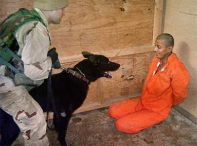 A US soldier in a flak jacket appears to be using both hands to restrain a dog facing an Iraqi detainee in the Abu Ghraib prison. The photo is one of the hundreds of unreleased pictures and videos that display techniques not seen in earlier images of prison abuse.